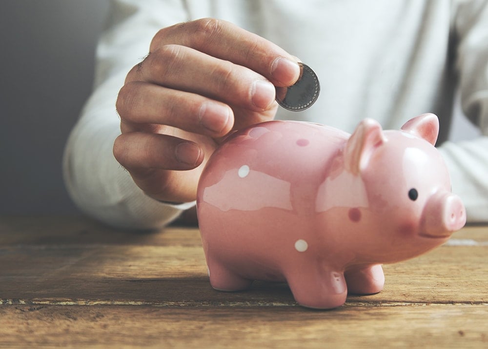 woman putting coin in piggy bank
