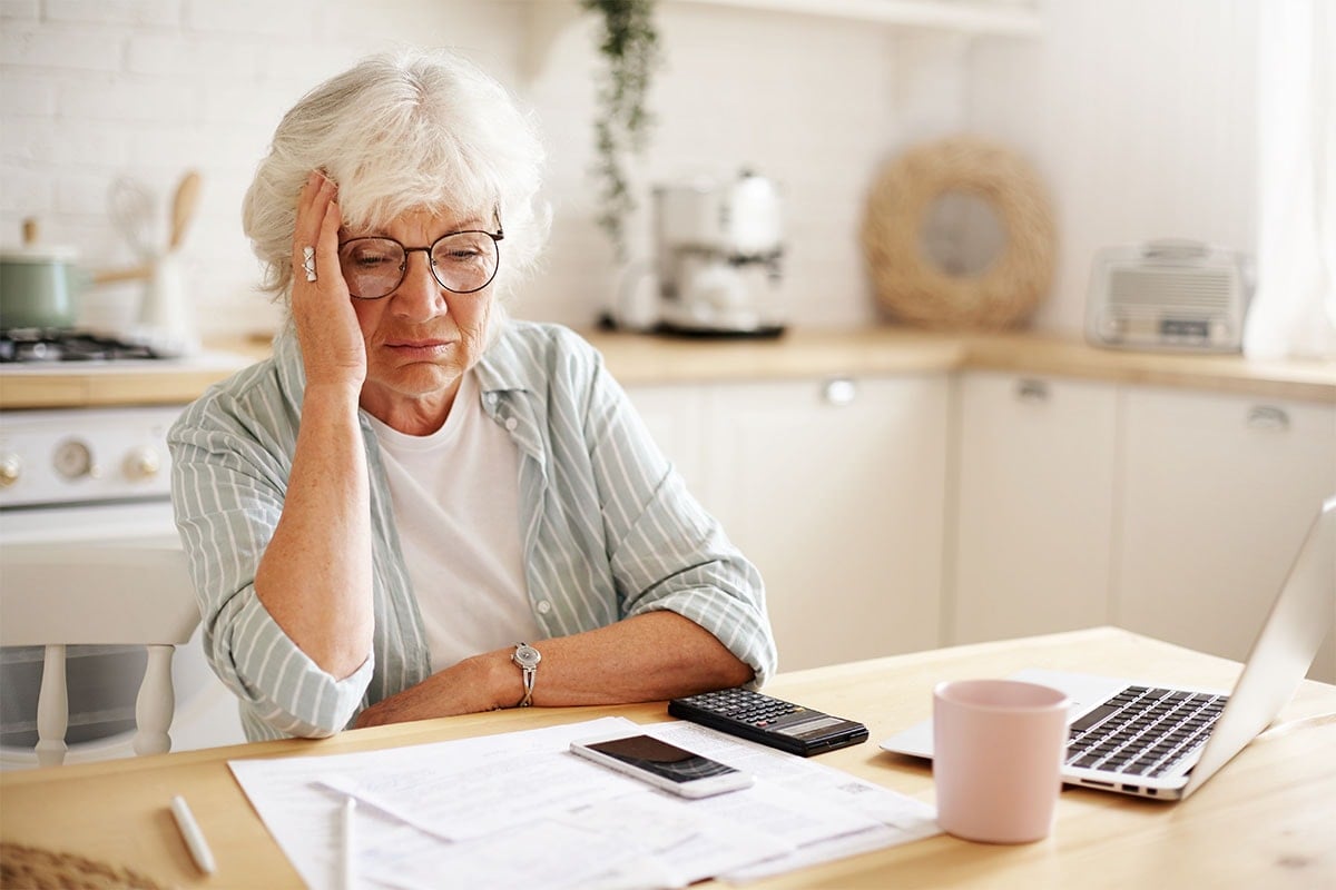 a stressed woman doing taxes at kitchen table