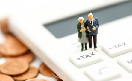 miniature retired couple on tax button