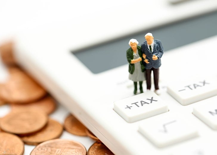 miniature retired couple on tax button