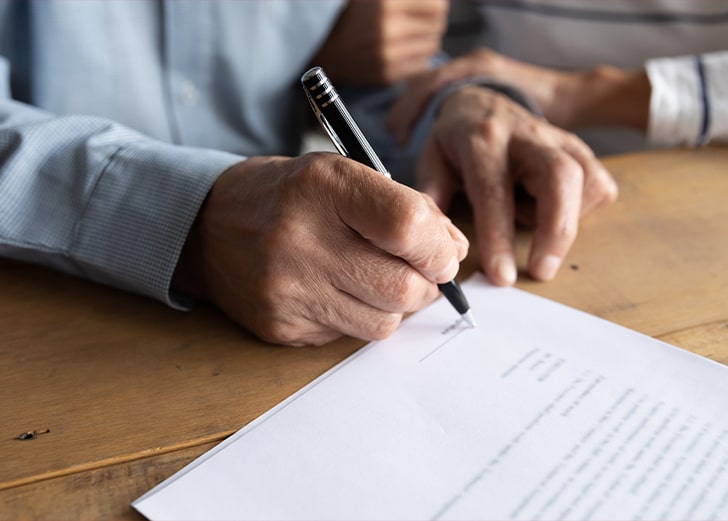 close up of older man signing estate planning papers