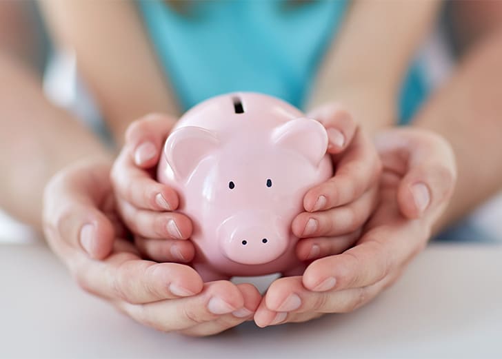 a child and parent holding a piggy bank