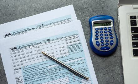 1040 tax forms with calculator pen at office desk