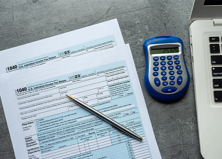 1040 tax forms with calculator pen at office desk