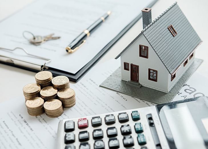 small house with a calculator, coins, keys, and a pen and paper