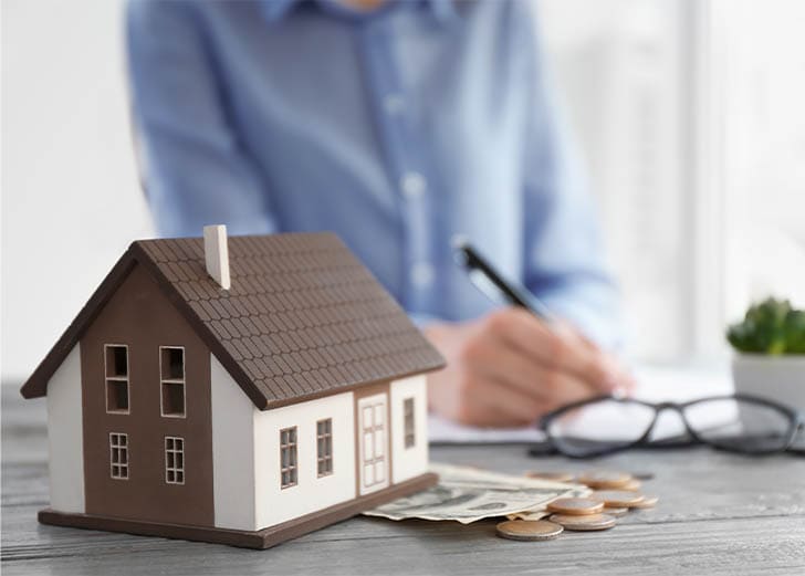 Figure of house and money on table of real estate agent